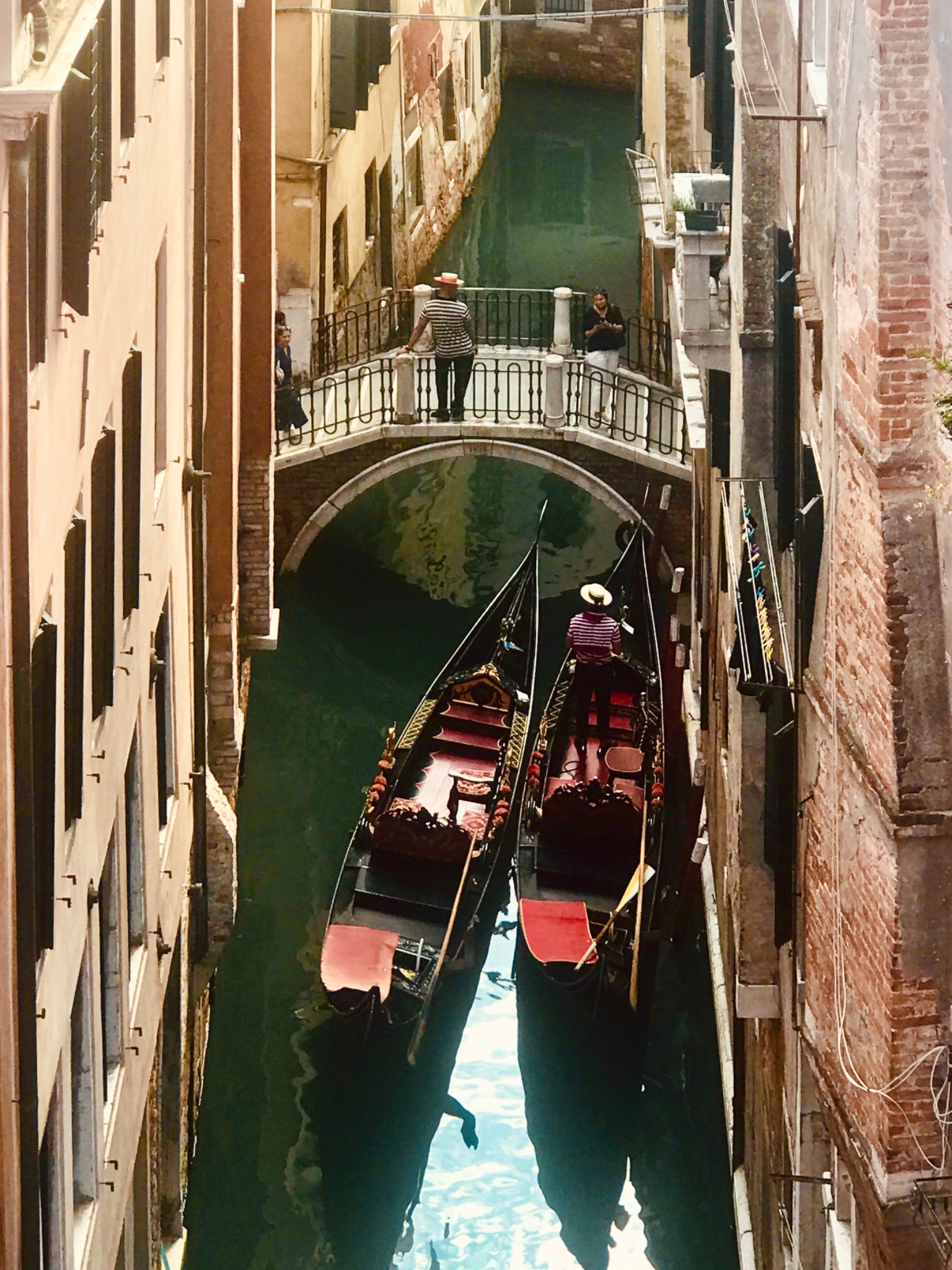 Gondolas passing beneath a small bridge on an intimate Venetian canal